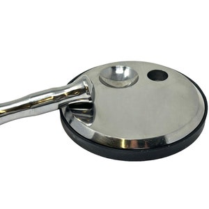 Puede incluir: Una base de metal plateado con una parte superior redonda y plana y una pequeña hendidura redonda. Un mango de metal plateado con forma cilíndrica está unido a la base.