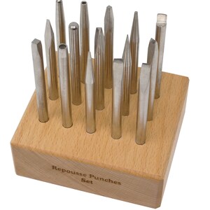 May include: A set of 16 metal repousse punches in a wooden holder. The holder has the words "Repousse Punches Set" engraved on the front.