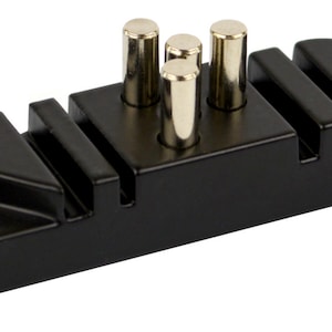 May include: Black metal tool with four metal pins and a triangular shaped edge. The tool has a logo that says "The Tool" with a blacksmith's anvil symbol.
