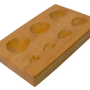 Peut inclure: Un outil en bois avec six dépressions arrondies de différentes tailles. L'outil est en bois brun clair et sert à façonner le métal.
