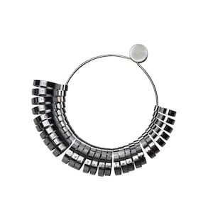 May include: A silver ring sizer with numbered rings, used for measuring finger size.