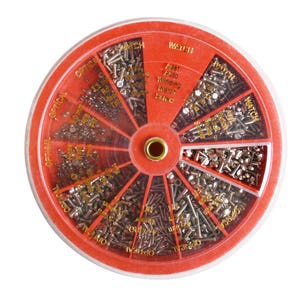 May include: A red, circular parts organizer filled with various small, silver screws. The organizer is divided into sections, with text labels including "OPTICAL" and "WATCH". The center has a gold-colored ring.