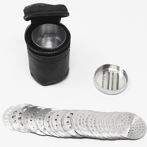 May include: A set of 32 stainless steel cookie cutters in a black leather carrying case. The case has a zipper closure and a small metal container inside. The cookie cutters are arranged in a row and are all different sizes and shapes.