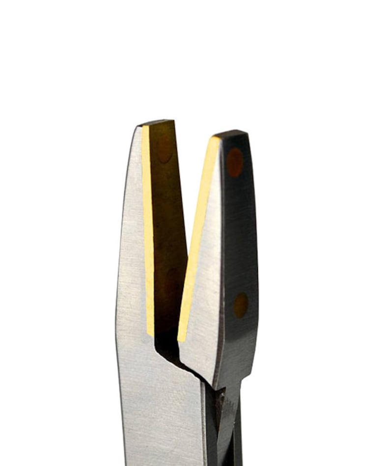 May include: Close-up of jewellery pliers with silver blades and gold-coloured inserts. The pliers have a black handle and are designed for precision work. The blades are sharp and angled, ideal for cutting or shaping metal.