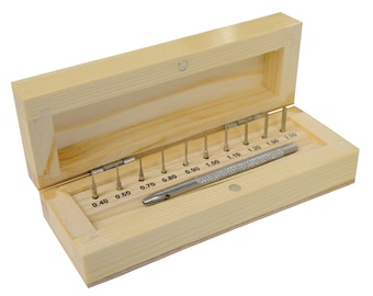 May include: A wooden box with a hinged lid, containing a set of precision drill bits and a knurled metal handle. The drill bits are arranged in ascending order, with sizes marked in inches. The box is made of light-colored wood.