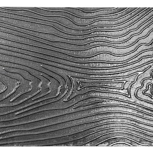 Op de afbeelding: Een close-up van een getextureerd metalen oppervlak met een patroon van golvende lijnen. Het oppervlak is zilverkleurig en heeft een metallic glans.