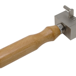 May include: A metal tool with a wooden handle, used for shaping metal. The tool has a series of grooves on the metal head, and a small lever on the side.
