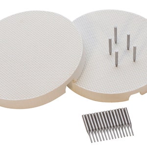 May include: Two white ceramic circular bases with a grid pattern and a set of 20 silver metal pins. The bases are used for pottery and ceramics.