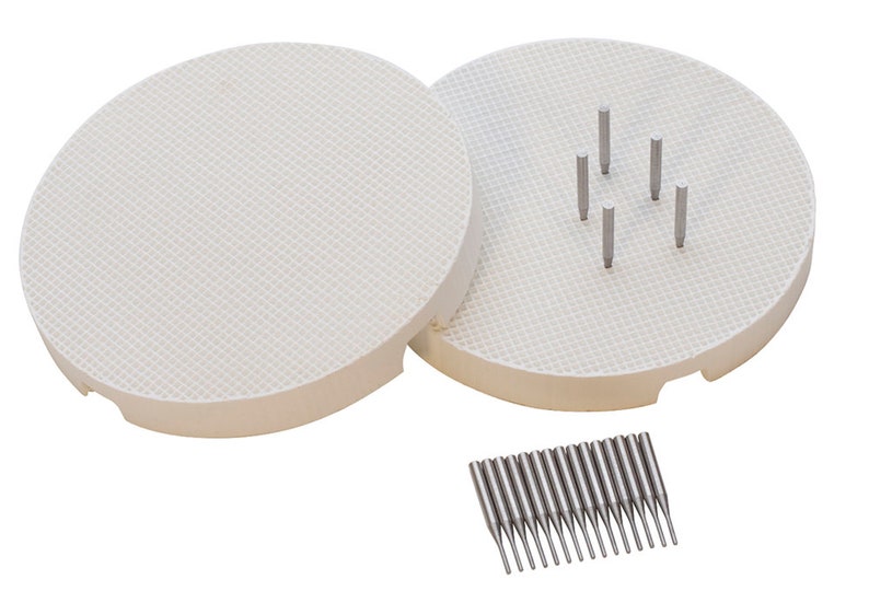May include: Two white ceramic circular bases with a grid pattern and a set of 20 silver metal pins. The bases are used for pottery and ceramics.
