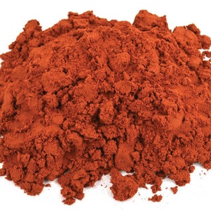 May include: A close-up of a pile of red paprika powder. The powder is finely ground and has a bright red color.