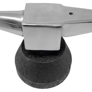 May include: A silver metal anvil with a black rubber base. The anvil has a pointed top and a flat surface.