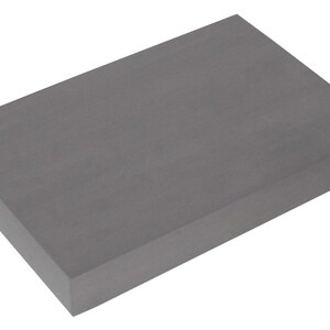 Op de afbeelding: Een grijze rechthoekige schuimblok. De blok is ongeveer 30 cm lang en 20 cm breed.