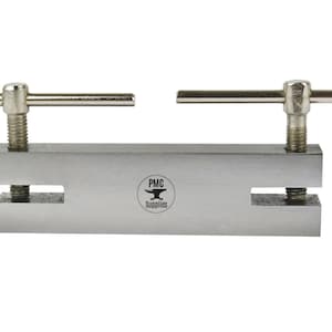 May include: A silver metal punch tool with two adjustable handles. The tool has two holes and the text "PMC Supplies" is printed on the front.