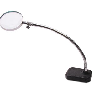 May include: A silver magnifying glass with a flexible gooseneck arm and a black base. The magnifying glass is attached to the arm with a knob.