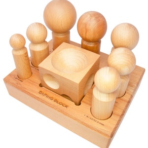 Puede incluir: Bloque de dafing de madera con un juego de punzones redondos de madera. El bloque tiene un hueco cuadrado con una depresión redonda en el centro. Los punzones están dispuestos en un círculo alrededor del bloque. El bloque está etiquetado como "DAFING BLOCK".