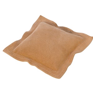 May include: A tan suede pillow with a decorative stitched edge.