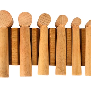 May include: Set of seven wooden mallets with rounded heads, arranged in a row on a wooden rack. The mallets are different sizes, with the largest on the left and the smallest on the right.