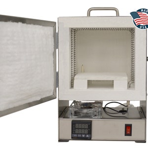 Peut inclure: Un four de couleur argentée avec la porte ouverte, révélant une isolation blanche et une étagère en céramique. Le four dispose d'un affichage numérique de la température et d'un interrupteur d'alimentation rouge. Un autocollant "Made in USA" est visible.