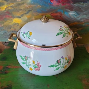 May include: White enamel pot with floral design and brass handles. The pot has a pink and white trim around the rim. The lid has a brass knob.
