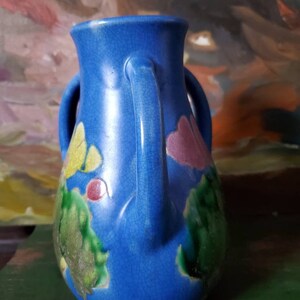 May include: A blue ceramic vase with two handles and a crackled glaze. The vase is decorated with green, yellow, and pink floral designs.