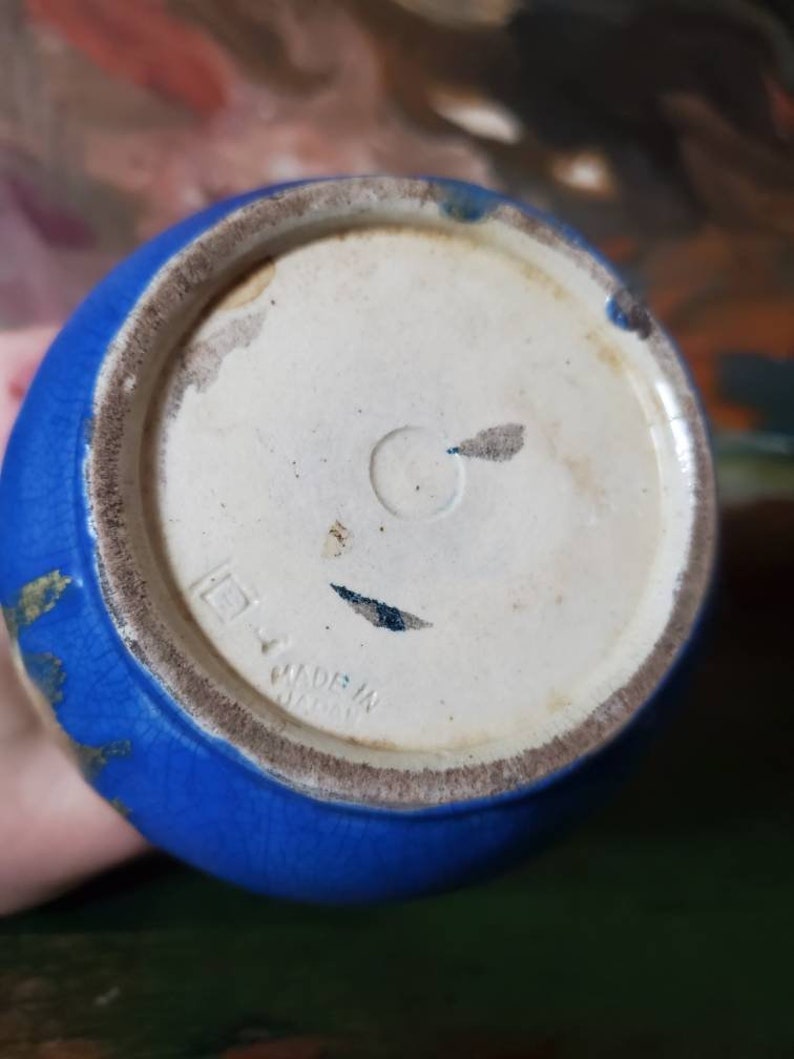 May include: Blue ceramic vase with gold accents and a white base. The base has the text "Made in Japan" printed on it.