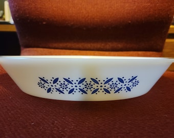 Op de afbeelding: Wit ovale ovenschaal met een blauw bloemmotief langs de rand. Ideaal voor bakken en serveren. De schaal is ongeveer 25 cm lang en heeft een klassiek ontwerp.