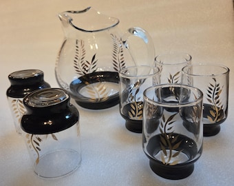 Vintage pitcher and glasses, black bases, gold leaf design, sold as a set.