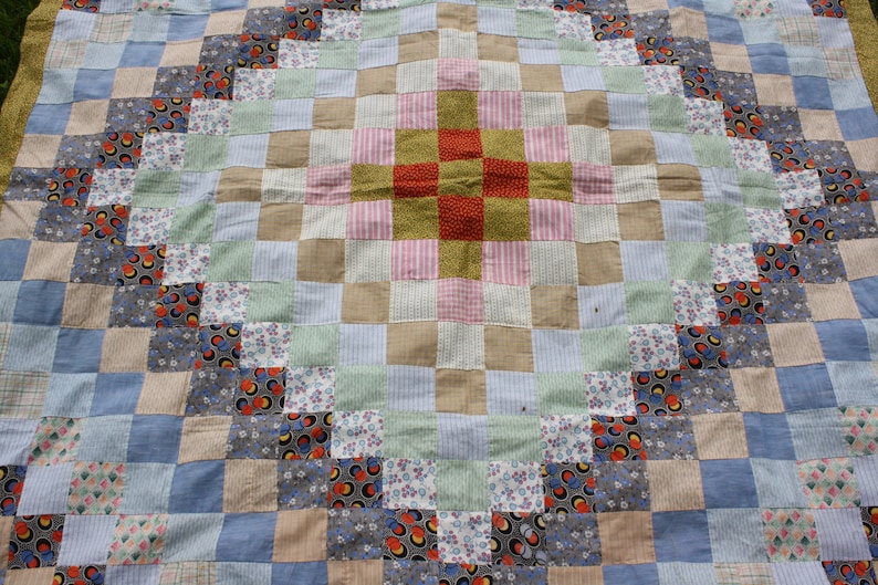 May include: A patchwork quilt with a central diamond pattern in shades of pink, green, and brown. The quilt is made of various fabrics with floral and geometric designs.