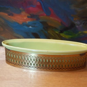 May include: A light green oval ceramic serving dish with a gold metal base. The base has a decorative openwork design.