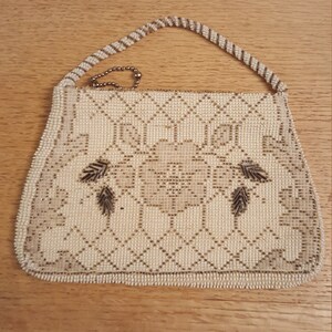 May include: A white beaded purse with a gold chain strap and a floral design. The purse is made of small, white beads that are woven together to create a delicate pattern.