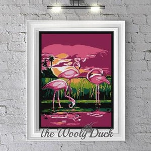 May include: A cross-stitch pattern featuring a pink sunset with three pink flamingos standing in a lake. The pattern is titled "The Woolly Duck".