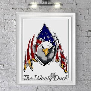 May include: A white bald eagle with its wings spread out, holding an American flag behind it. The eagle's head is facing forward, and its eyes are closed. The flag is red, white, and blue, and it is torn in the middle, revealing the eagle's body. The image is in a white frame with the text "The Woolly Duck" at the bottom.