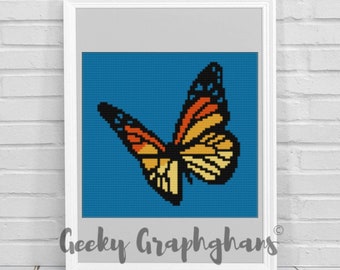 Op de afbeelding: Een ingelijst kruissteekpatroon van een vlinder met oranje, gele en zwarte vleugels tegen een blauwe achtergrond. De tekst "Geeky Graphghans" staat onderaan het frame.