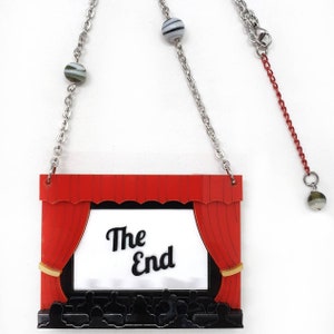 May include: A red and black movie theater curtain with the words "The End" on a white screen. The curtain is hanging from a silver chain with black and white striped beads.