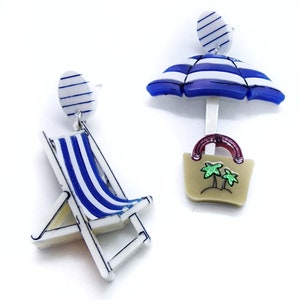 Lasergesneden oorbellen van acryl en plexiglas in de vorm van een strandstoel en een parasol.
