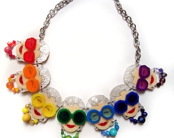 May include: A colorful necklace with a chain and seven white pendants, each featuring a cartoon face with sunglasses in a different color of the rainbow.