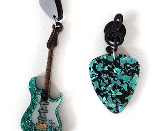 May include: A pair of dangle earrings featuring a green glitter electric guitar and a green glitter guitar pick with a black treble clef charm.