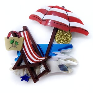 Può includere: Un ombrellone da spiaggia a strisce rosse e bianche con una sedia a sdraio in legno, una borsa marrone con palme e una scena di spiaggia blu e bianca.