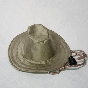 Puede incluir: Un sombrero de sol verde caqui con un ala ancha y un cord&oacute;n.