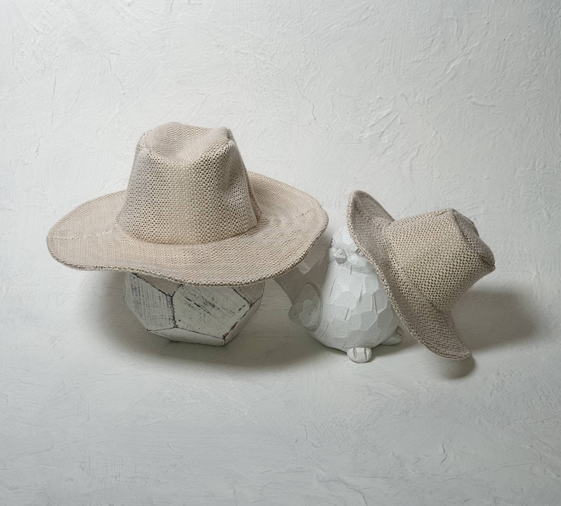 Puede incluir: Dos sombreros de vaquero de paja beige, uno m&aacute;s grande que el otro, est&aacute;n sentados encima de esculturas de cer&aacute;mica blanca. Las esculturas tienen forma de bal&oacute;n de f&uacute;tbol y de p&aacute;jaro.