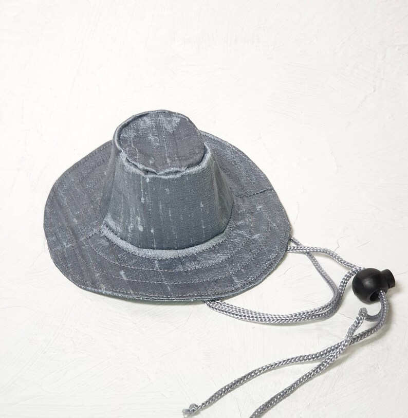 Puede incluir: Un sombrero de sol gris de ala ancha con una corona cinchada y un cord&oacute;n de ajuste gris.