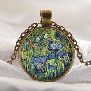 May include: A round glass pendant necklace with a bronze chain. The pendant features a painting of blue irises against a green background.