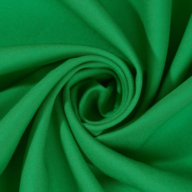 May include: A close-up of a vibrant green fabric, folded and twisted into a swirling pattern. The fabric has a smooth, silky texture.