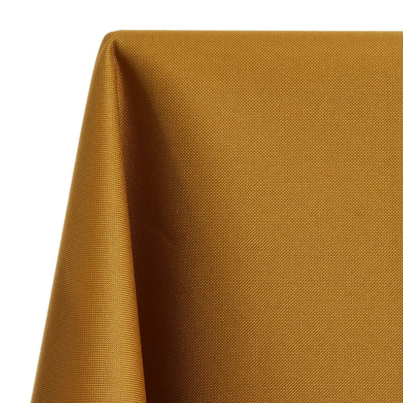 May include: A close-up of a gold fabric tablecloth with a textured weave.