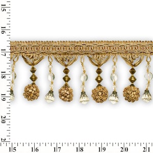 Puede incluir: Borde dorado con flecos de cuentas y detalles de cristal. El fleco presenta pequeños pompones dorados.