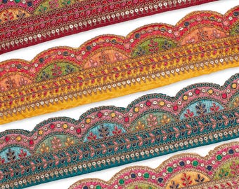May include: Close-up of four colorful, embroidered trims with a scalloped edge. The trims feature intricate floral and geometric patterns in shades of red, yellow, teal, and gold, embellished with sequins and metallic thread. These trims are ideal for adding decorative detail to fabric projects.