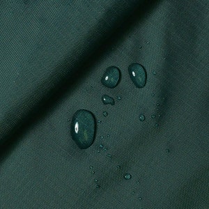 Puede incluir: Primer plano de una tela verde oscuro con gotas de agua en la superficie. La tela es lisa y tiene una textura sutil. Las gotas de agua son redondas y transparentes, y están espaciadas uniformemente sobre la superficie de la tela.