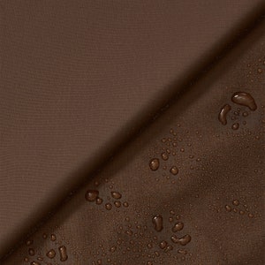 Pode incluir: Close-up de tecido castanho com um padrão de grade subtil. O tecido é dobrado diagonalmente, com gotas de água no lado inferior direito, sugerindo um material resistente à água. A cor é um castanho rico e terroso.