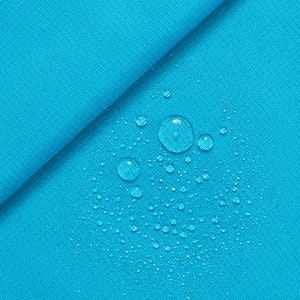 May include: Close-up of turquoise fabric with water droplets. The fabric has a textured weave and is folded diagonally across the frame. Several clear water droplets of varying sizes are scattered across the surface, creating a refreshing visual.