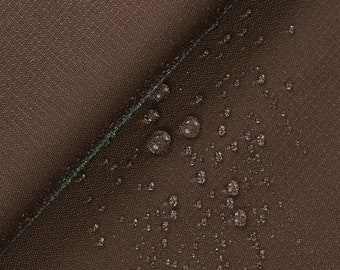May include: Close-up of a brown fabric with water droplets on the surface. The fabric has a subtle texture and appears to be water-resistant.